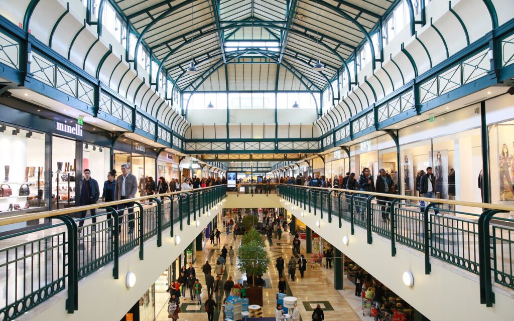 Vue du centre commercial Val d’Europe sur deux niveaux avec boutiques et familles en promenade.